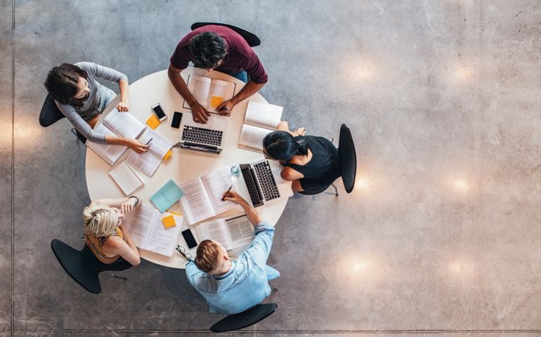 Top view of group of students sitting together at table. University students doing group study.