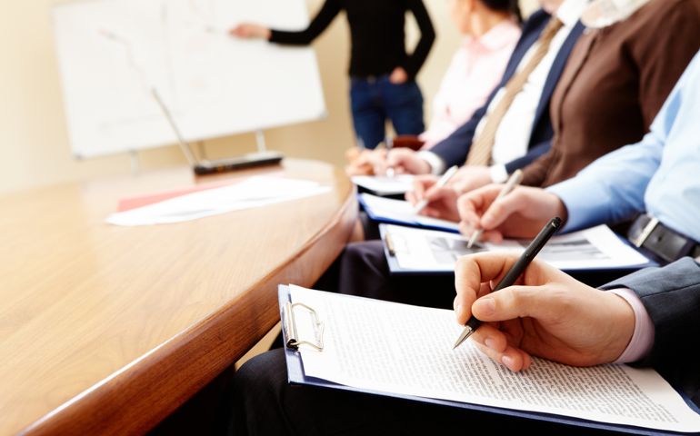 Close-up of businesspeople hands holding pens and papers near table at business seminar