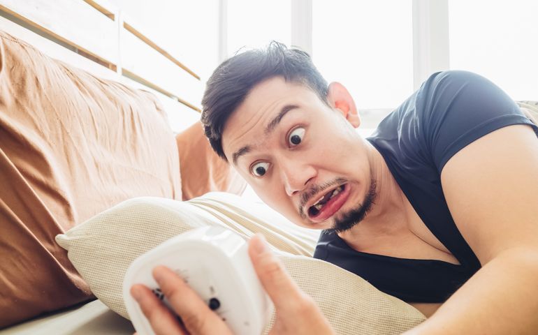 Funny face Asian man shocked as he wakes up late for an appointment.