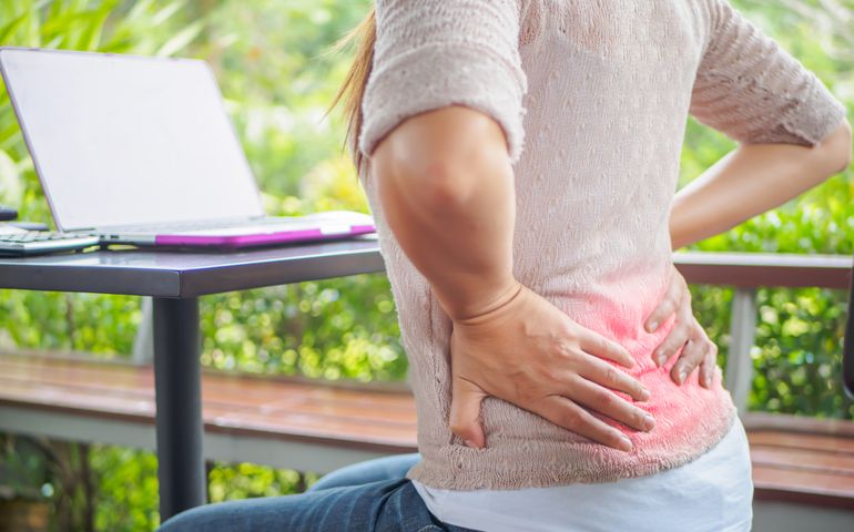 Closeup woman with hands holding her back pain. Office syndrome and Health-care Concept.