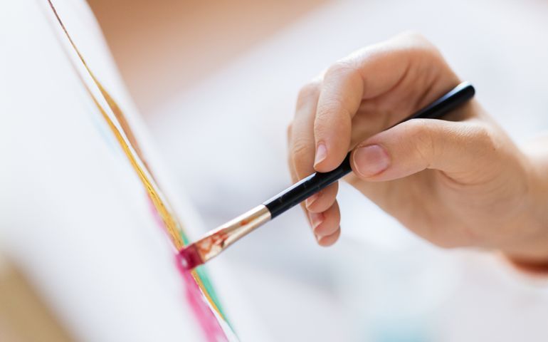 art, creativity and people concept - hand of artist with brush painting picture
