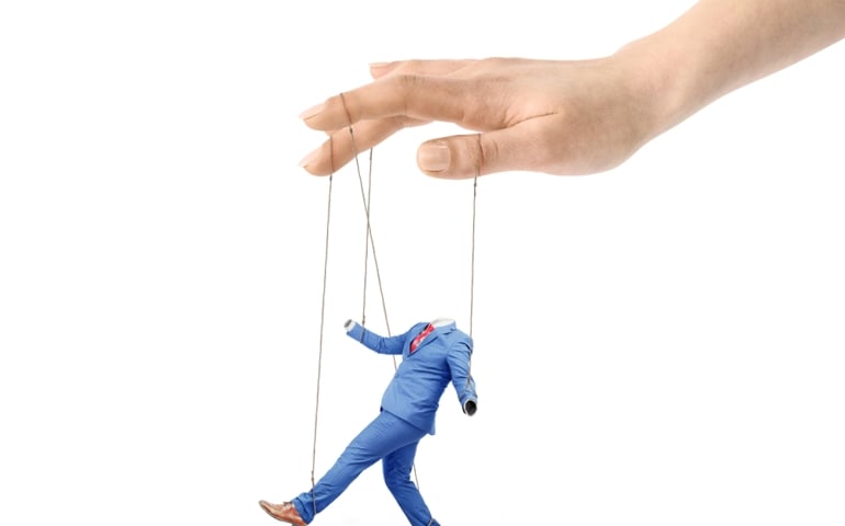 A hand controls a worker on a white background. Submission of will. Puppet master.