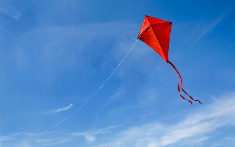 A red kite flying against a blue sky.