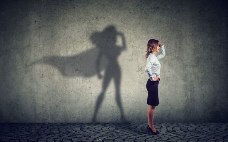 Side view of a business woman imagining to be a super hero looking aspired.
