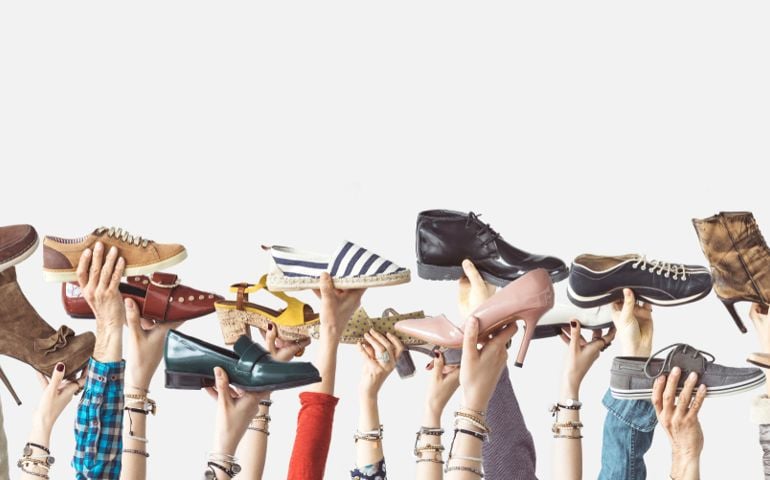 Hands holding different shoes on isolated background