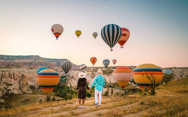 happy young couple during sunrise watching the hot air balloons of Kapadokya Cappadocia Turkey
