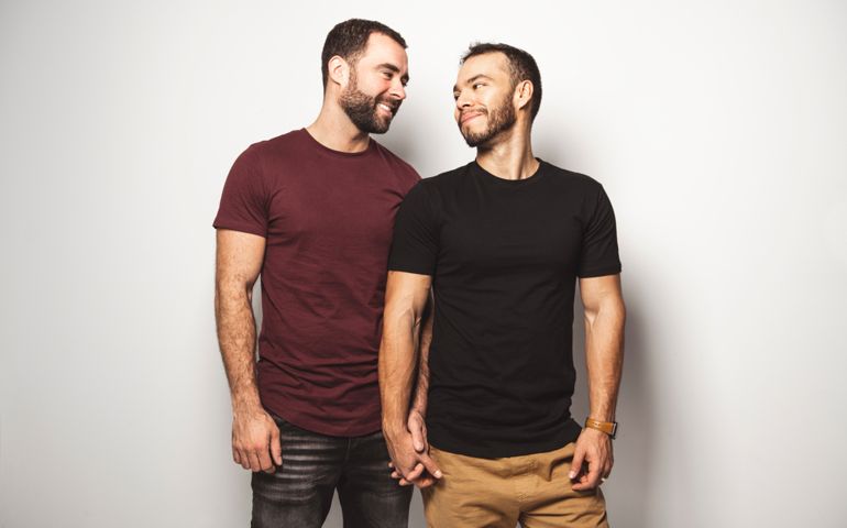 Young homosexuals gay couple love each other on a white background.
