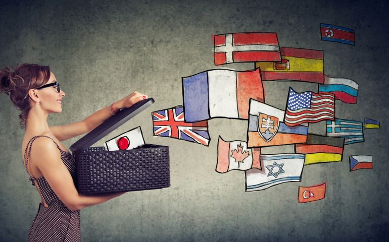 Young woman speaks different languages opening a box with international flags flying away
