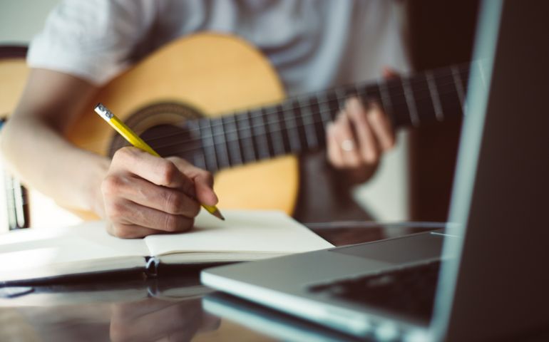 songwriter thinking and writing notes,lyrics in book at studio.man playing live acoustic guitar.concept for musician creative.artist composer in work process.people relaxing time with instrument