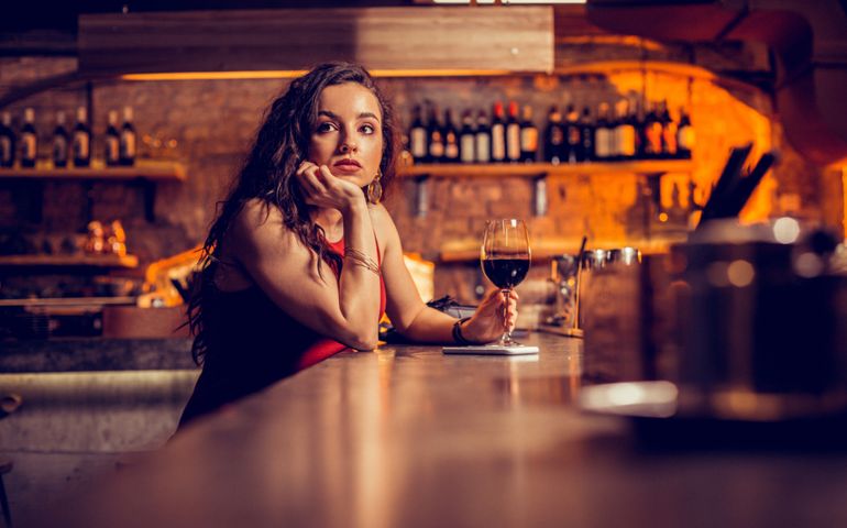 Drinking and waiting. Long-haired curly woman drinking wine and waiting for her man in the bar