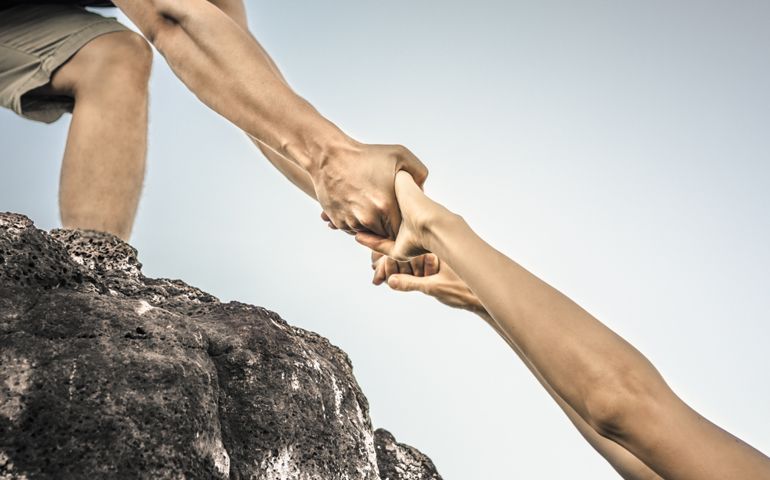 Giving a helping hand up a mountain. Helping someone in need concept.