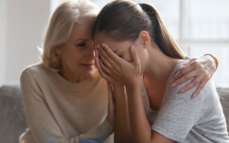 Worried aged mother embracing comforting grown up daughter with broken heart family sit on sofa, elderly mom soothe crying adult child, divorce or miscarriage, share problem with someone close