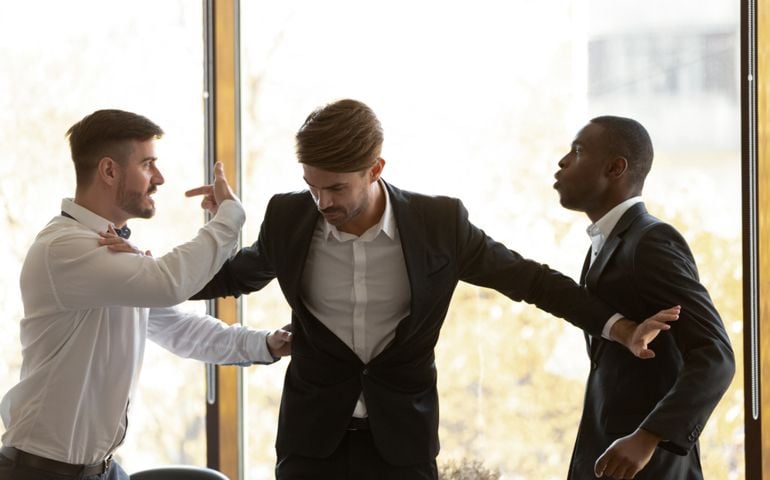 Male colleague set apart angry diverse business men coworkers argue fighting at corporate office meeting, mad employees quarreling shouting having conflict at work, racial hatred harassment concept