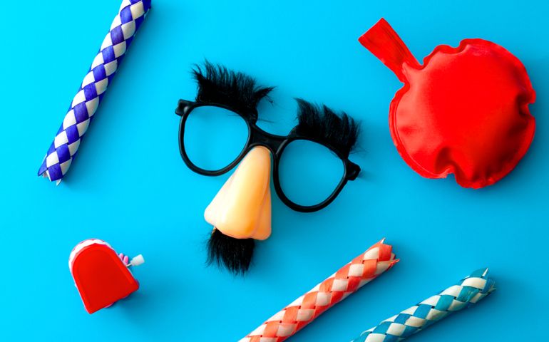 Comical prank, April fools practical joke and goofy disguise concept farting bag, chattering teeth, chinese finger trap and novelty glasses with fake nose and eyebrows isolated on blue background