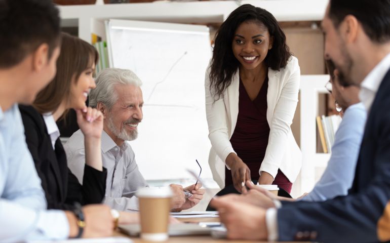 Different ethnicity and age businesspeople gathered together at boardroom for negotiations and planning future collaboration lead by african smiling businesswoman or corporate training process