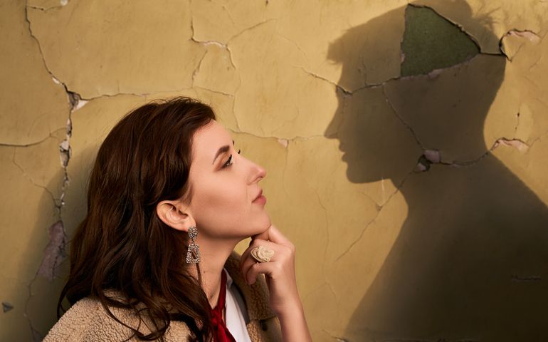 Beautiful througtful young woman thinks of her ideal boyfriend man or lover represented by a shadow on the wall.