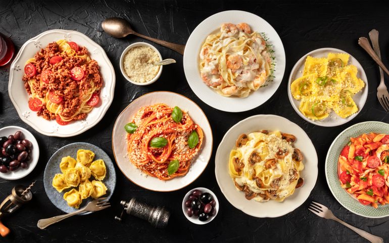 Pasta. Assortment of Italian pasta dishes, including spaghetti Bolognese, penne with chicken, tortellini, ravioli and others, shot from the top on a black background