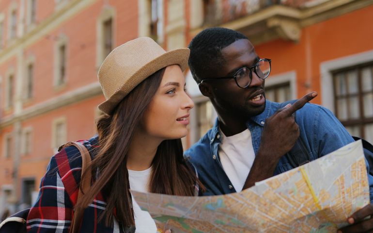 Lost multi-ethnic confused couple of tourists using city map on square on weekend.