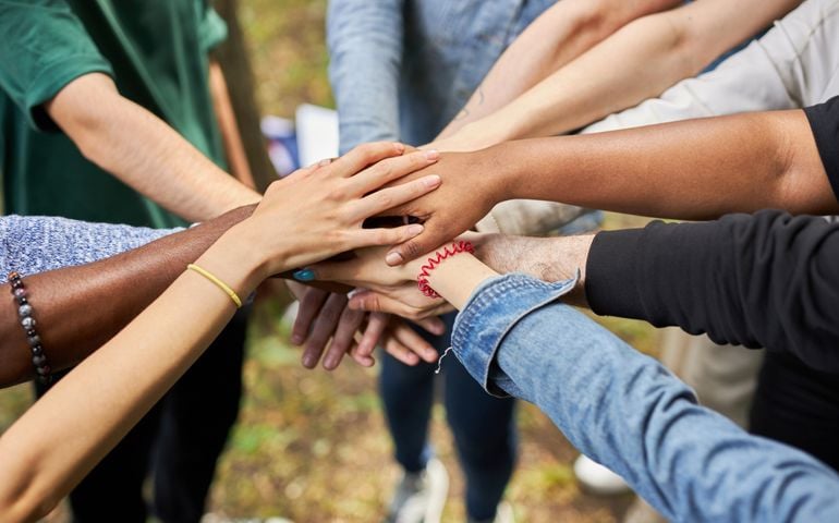 close-up photo of diverse people's hands gathered together, african american and caucasian people as one union. various ethnicities are friends all over the world