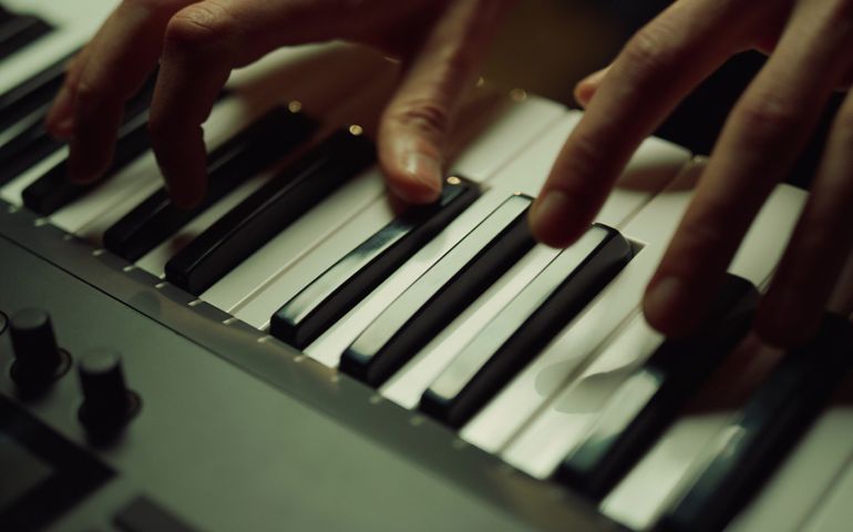 Unknown composer producing melody with piano in music studio.