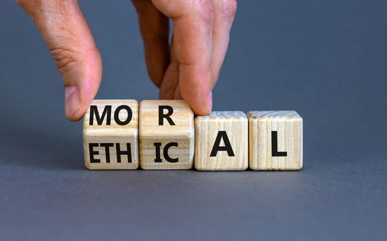 Ethical or moral symbol. Businessman turns wooden cubes and changes the word 'moral' to 'ethical' on a beautiful grey table, grey background. Business and ethical or moral concept.