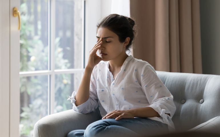 Indian woman suffering from headache, migraine, touching face, head with closed eyes, feeling stressed, sick, tired