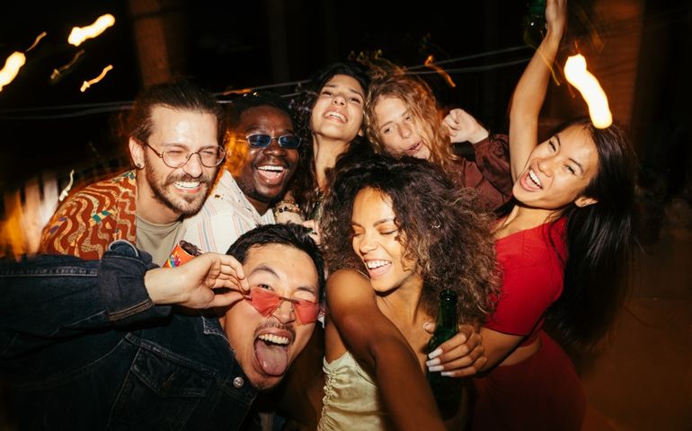 A group of multiracial friends has a great time at the roof nightclub in the summertime. Clubbing, fun, and parties during the summer concept.