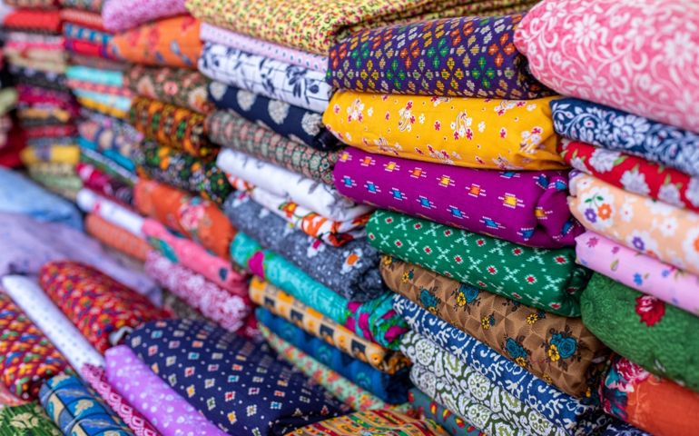 Cotton fabrics. Natural multi-colored fabrics with various patterns and patterns are in large piles in fabric store. Different textures of fabrics. Textile production and sale. Natural bright dyes.