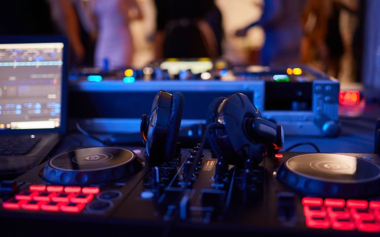 DJ console cd mp4 deejay mixing desk Ibiza house techno dance music wedding reception party in nightclub with colored lighting effect disco lights