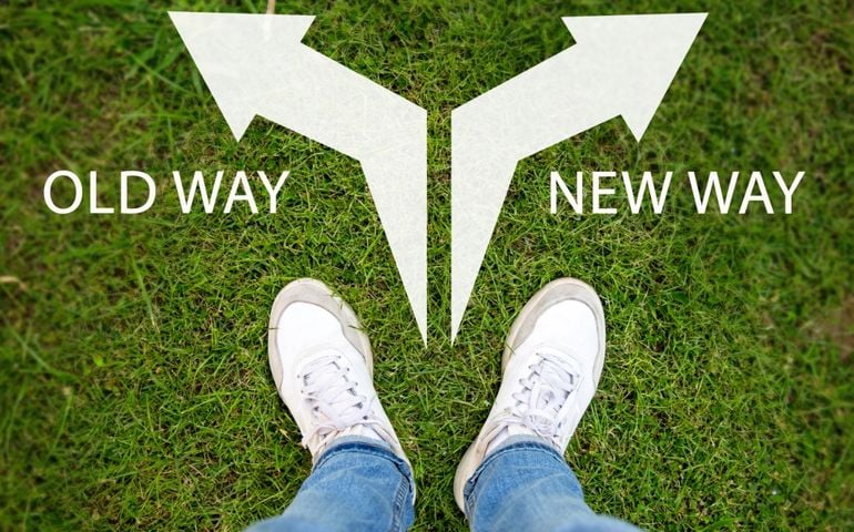 A businessman standing in a grassy garden Deciding whether to choose an old way or a new way