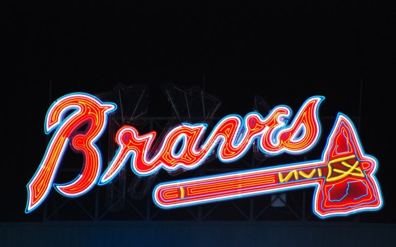 A large neon sign depicting the name and logo of the Atlanta Braves baseball team is illuminated at night