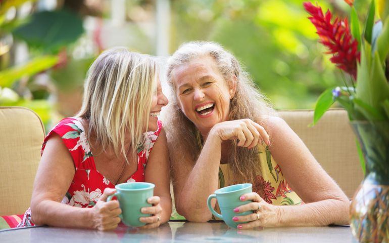 Pair of cute middle aged female friends laughing