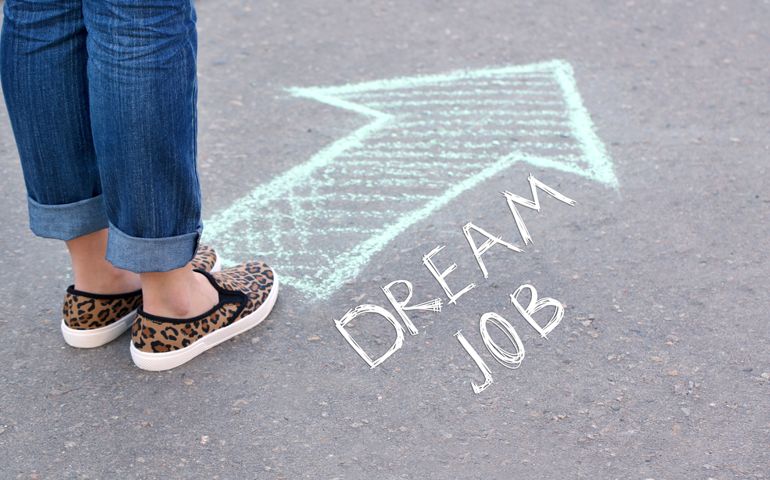 Dream job concept. Female feet and drawing arrow on pavement background