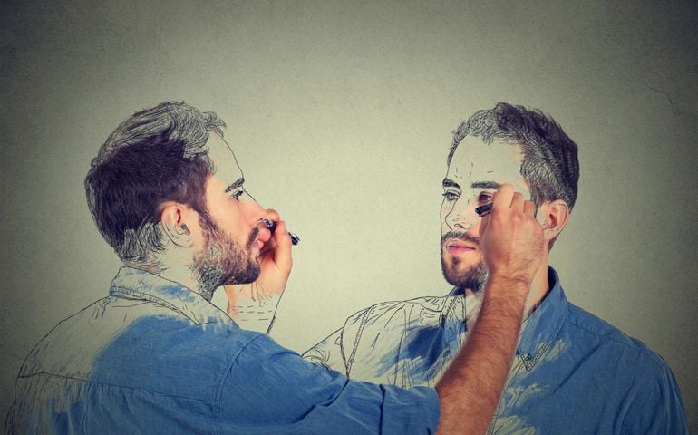 Create yourself concept. Good looking young man drawing a picture, sketch of himself on grey wall background. Human face expressions, creativity