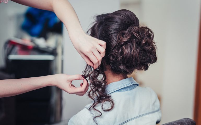 Closeup hairdresser coiffeur makes hairstyle.