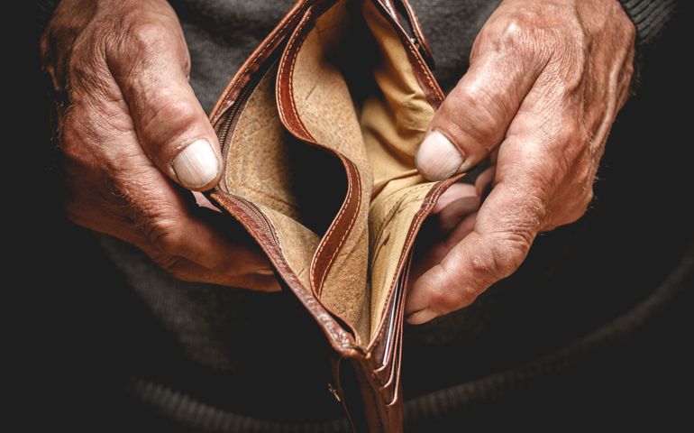 Empty wallet in the hands of an elderly man. Poverty in retirement concept