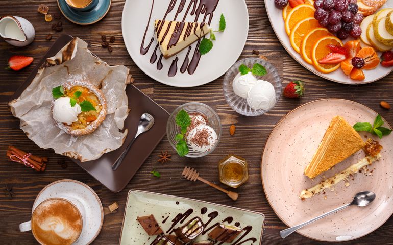 Different desserts with fruits and coffee, top view