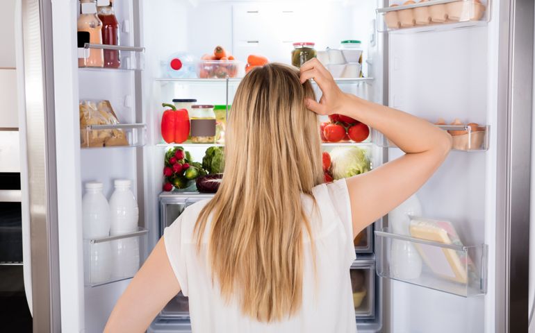 Rear View Of Young Woman Looking In Fridge At Kitchen