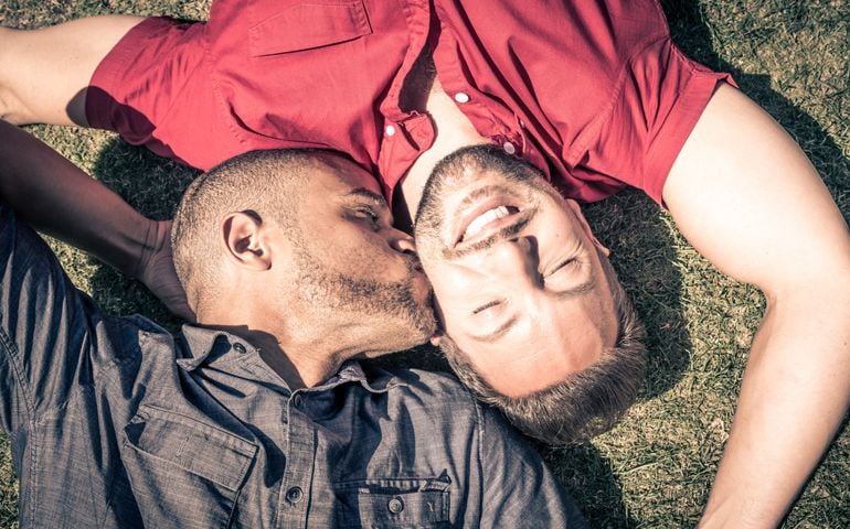 Happy gay couple lying down on the grass