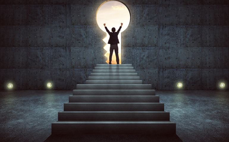 Success businessman cheering on stair against concrete wall with key hole door ,sunrise scene city skyline outdoor view .
