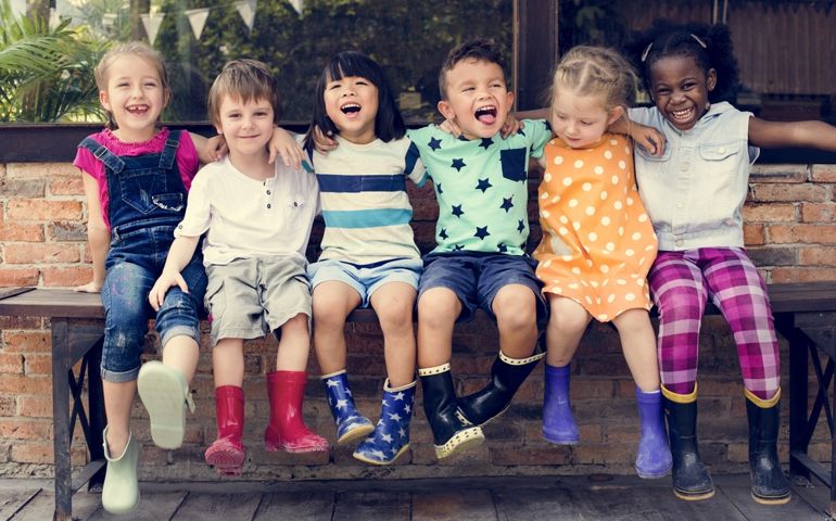 Group of kindergarten kids friends arm around sitting and smiling fun