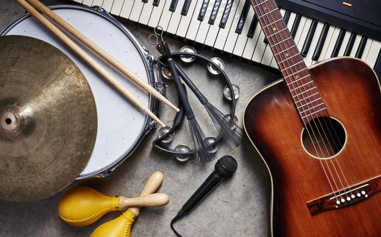 a group of musical instruments including a guitar, drum, keyboard, tambourine.