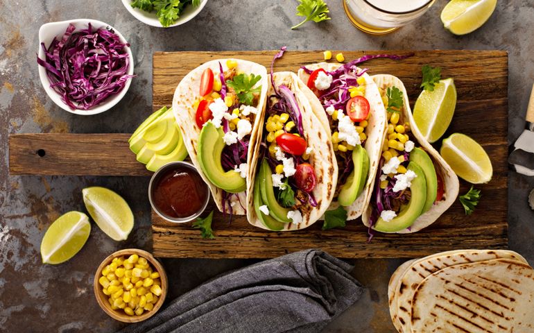 Pulled pork tacos with red cabbage, tomatoes, corn, feta and avocados overhead shot