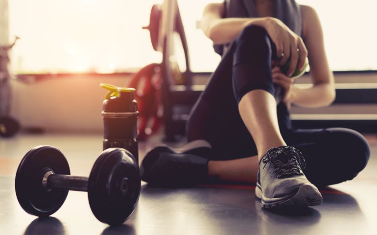Woman exercise workout in gym fitness breaking relax holding apple fruit after training sport with dumbbell and protein shake bottle healthy lifestyle bodybuilding, Athlete builder muscles lifestyle.
