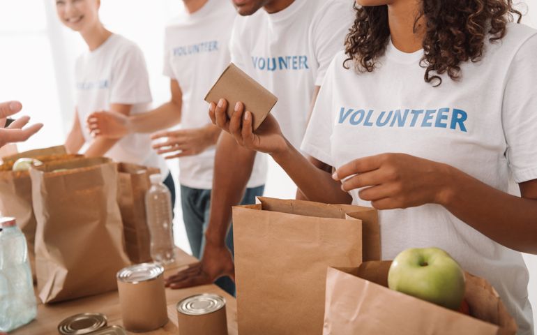 cropped shot of young volunteers group packing food and drinks for charity