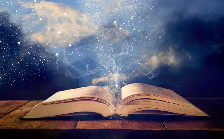 image of open antique book on wooden table with glitter overlay