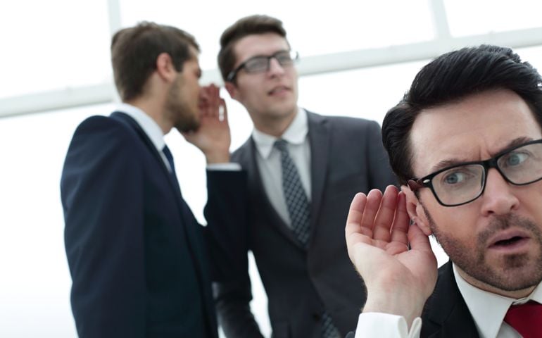 close up.businessman eavesdropping on conversation between colleagues