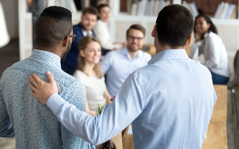 New mixed race employee having first working day in company standing in front of colleagues, executive manager employer introducing welcoming newcomer to workmates. Human resources employment concept