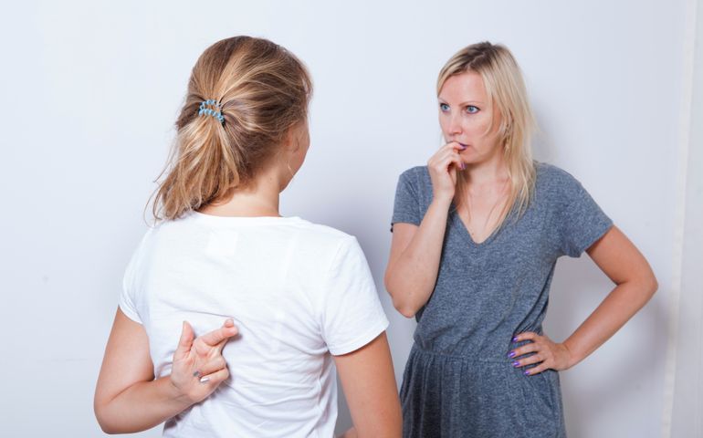 Mother asking her teenage daughter. Girl wants to lie to her parent and crossed her fingers.