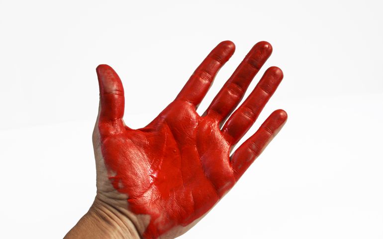 ht red handed. Hand and palm covered in bright red paint, resembling blood or thief and stealing